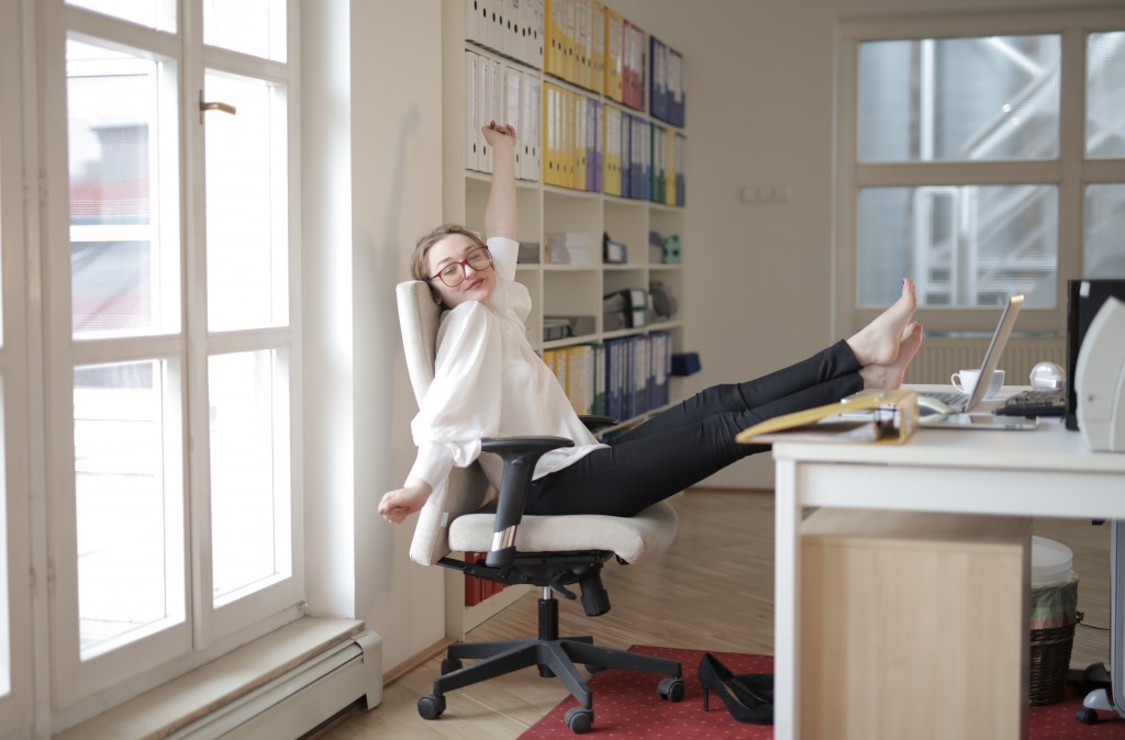 オフィスチェアで足を机に放り出しリラックスする女性